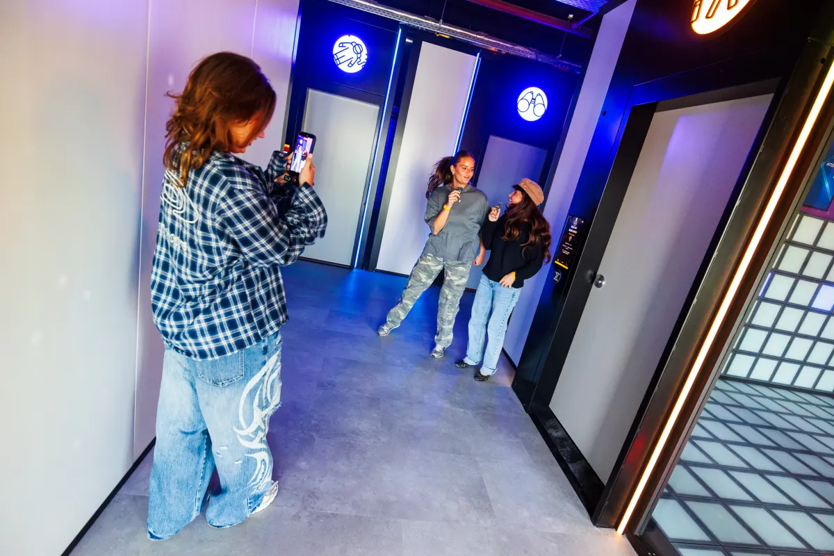 A creator films two guests with microphones in the mission hallway at Time Mission